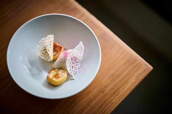 Fine-dining dish at Hillside Kitchen with delicate lattice crisps and small plated bites in a ceramic bowl on a wooden table.