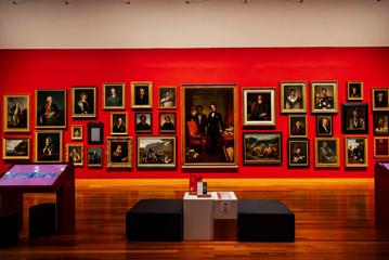 A red wall with more than 20 portrait paintings inside Museum of New Zealand Te Papa Tongarewa.