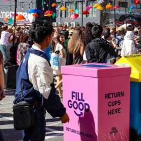 A crowd at CubaDupa in front of colourful reusable serviceware bins.