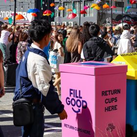 A crowd at CubaDupa in front of colourful reusable serviceware bins.