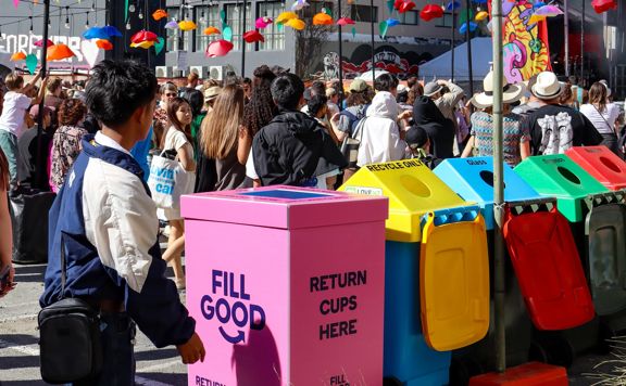 A crowd at CubaDupa in front of colourful reusable serviceware bins.