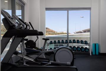 A treadmill, elliptical and bicycle machine and a variety of weights inside a hotel gym.