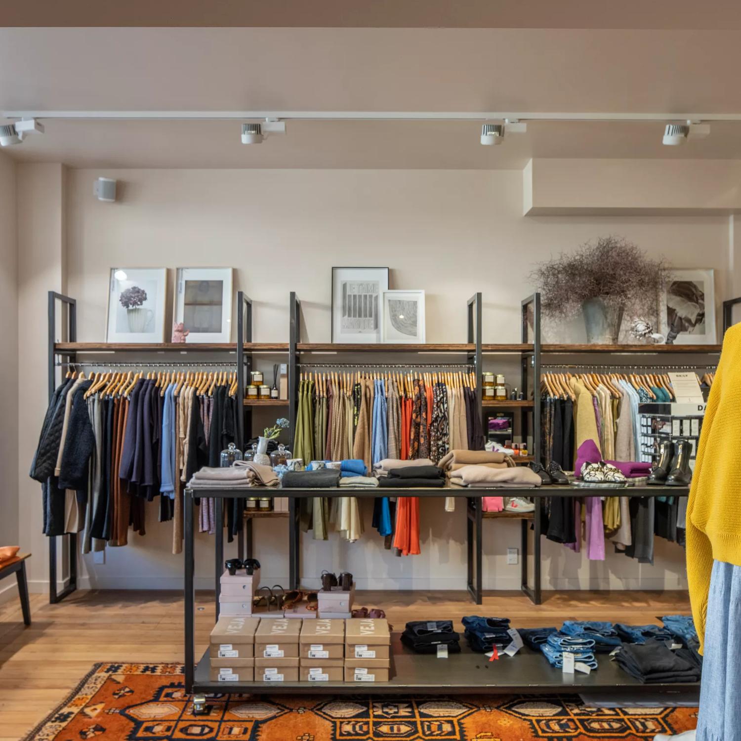 The interior of Goodness. Along the back wall are racks of clothing. In the middle sits a display of jumpers and shoes. And in the foreground, a mannequin wears a yellow jumper and denim skirt.