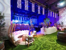 Shed 6 set up for an event with fake grass on the ground, seating areas and spiral pattern light effects.