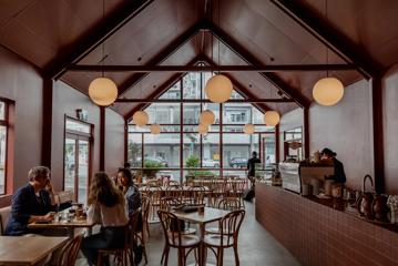 Wide view of the interior of August Eatery in Wellington, looking towards the windows. Friends are at a table talking.