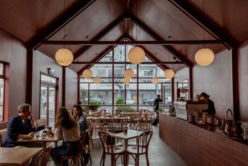 Wide view of the interior of August Eatery in Wellington, looking towards the windows. Friends are at a table talking.