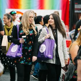 Two women with purple tote bags walk through the Wellington Women's Lifestyle Expo.