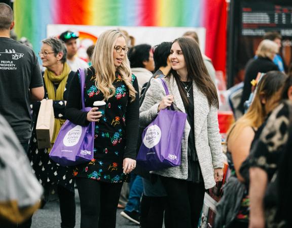 Two women with purple tote bags walk through the Wellington Women's Lifestyle Expo.