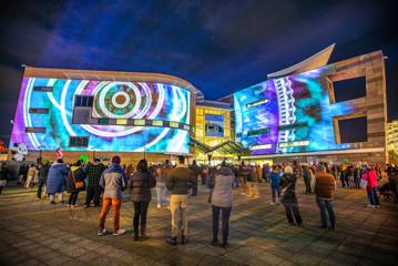 People gather and watch a light projection on the exterior of Te Papa at Wellington's waterfront to celebrate Matariki.