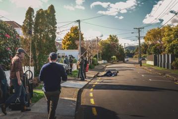 Behing the scenes of Wellington Paranormal, a comedic television series. The cast and crew are shooting a scene on a suburban street.