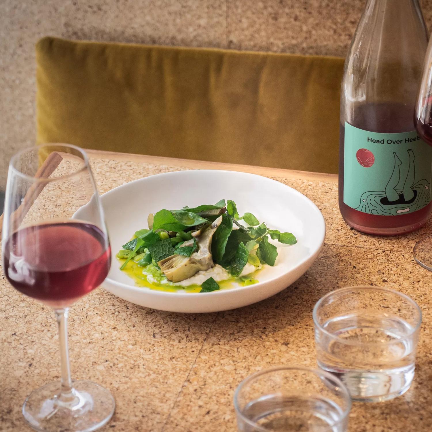 A green dish served at Rita, with a glass of red wine and a bottle next to it.