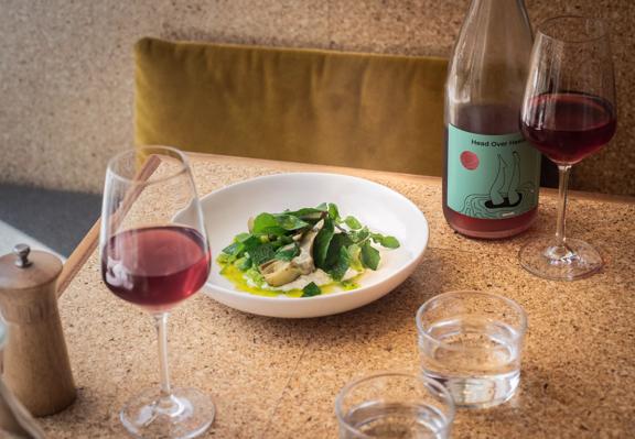 A green dish served at Rita, with a glass of red wine and a bottle next to it.