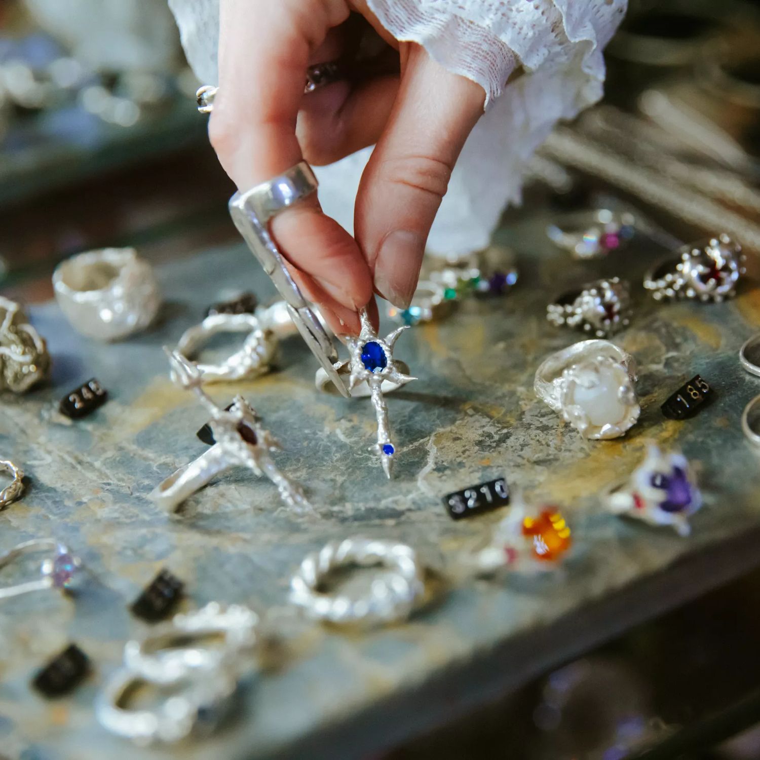 A hand picking up a ring from a jewellery display case.