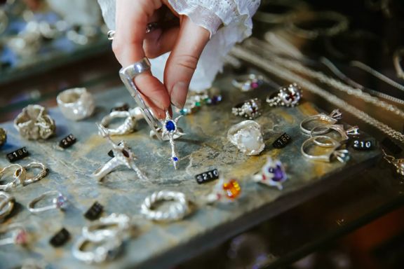 A hand picking up a ring from a jewellery display case.