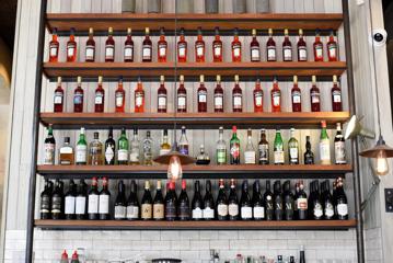 Five stacked wooden shelves with bottles of wine and liquor on display.