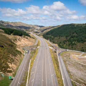 The 4 lane motorway of Transmission Gully, surrounded by green hills.