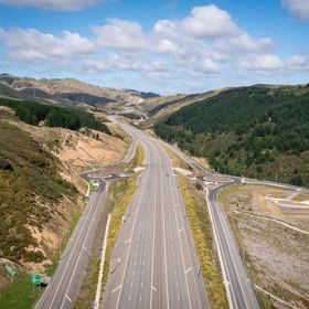 The 4 lane motorway of Transmission Gully, surrounded by green hills.