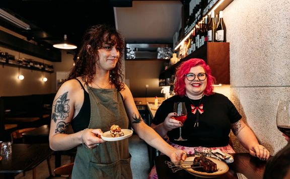 A server delivers two small sharing plates to a table at Rosella.