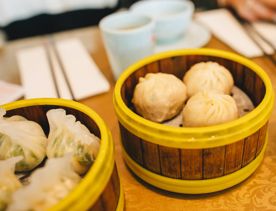 A wooden bowl with three steamed dumplings inside.