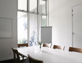 A smaller meeting room inside Zealandia venues, with a white table and 8 chairs.