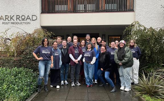 A group of students smiling standing outside a film post production studio