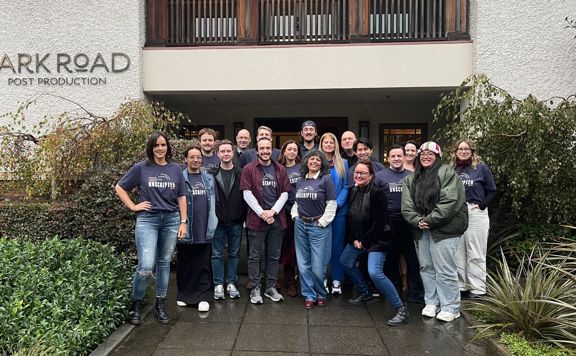 A group of students smiling standing outside a film post production studio