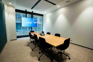 A boardroom inside Generator, with 8 chairs around a rectangle table, and a tv screen on the wall.