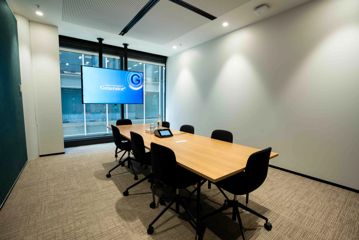 A boardroom inside Generator, with 8 chairs around a rectangle table, and a tv screen on the wall.