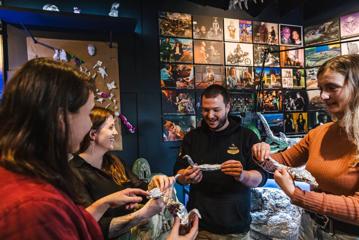 Four people stand in a semi-circle, each holding an aluminium foil figurine shaped like a bird.