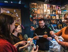 Four people stand in a semi-circle, each holding an aluminium foil figurine shaped like a bird.