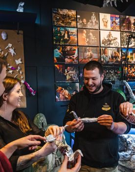 Four people stand in a semi-circle, each holding an aluminium foil figurine shaped like a bird.