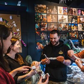 Four people stand in a semi-circle, each holding an aluminium foil figurine shaped like a bird.