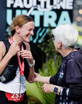 A smiling runner greets a Faultline Ultra volunteer.
