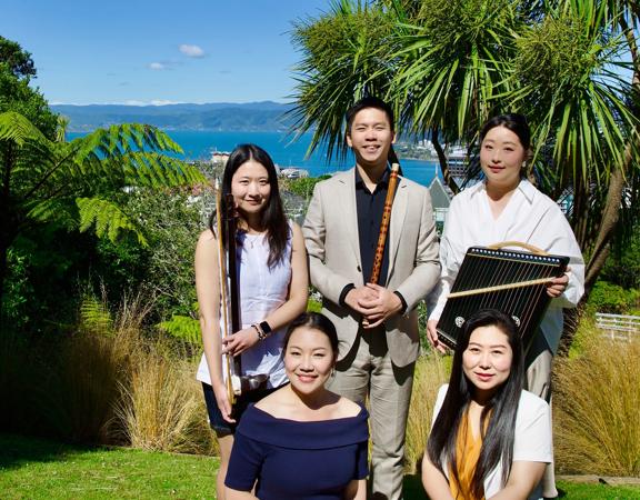 The five members of the Eastern Echoes Ensemble pose with their instruments with a view of Wellington harbour behind them.