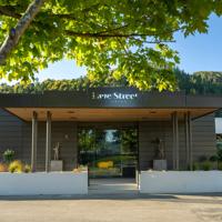 The front exterior of Lane Street Studios in Upper Hutt. A veranda with a name sign sits over the glass front doors. White planter boxes sit out front.