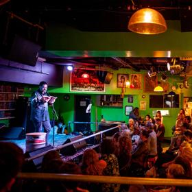 A person on stage with a microphone reads a book to a packed audience at the Verb Readers and Writers Festival in Wellington.