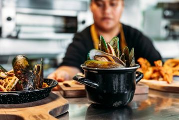 Waitstaff in The Crab Shack serve plates of mussel and pasta.