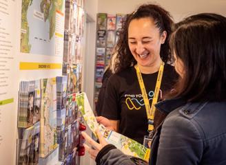 A team member from the isite helps a customer look at a map of Wellington, and they share a laugh.