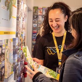 A team member from Isite helps a customer look at a map of Wellington, and they share a laugh.