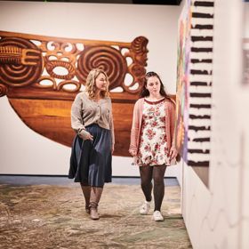 Two people look at the art on display at Te Whanganui a Tara exhibition, Wellington Museum.