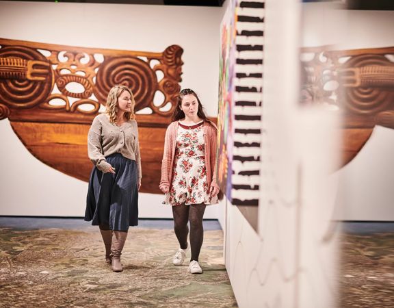Two people look at the art on display at Te Whanganui a Tara exhibition, Wellington Museum.