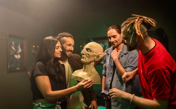 Four people look at a model bust of a character from The Lord of the Rings during a tour at Wētā Workshops.