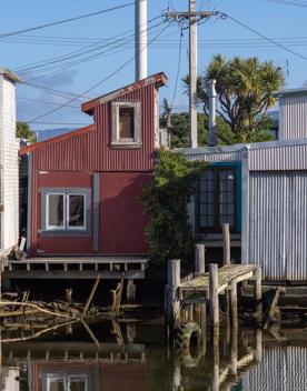 The Petone boat ramp, Hikoikoi,  with colourful boat sheds and boats in the morning sun.