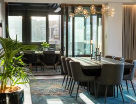 The indoor outdoors flow of TRYP by Wyndham Wellington, with a dining table inside and one outside.