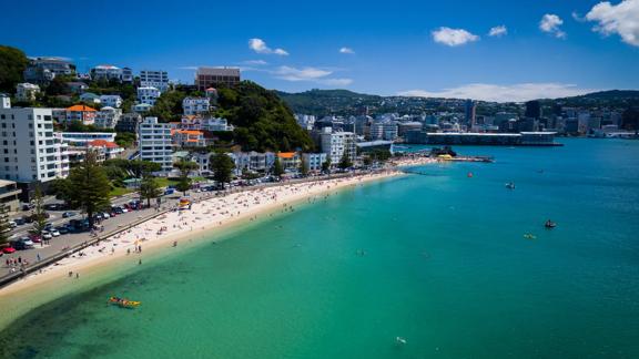 Drone shot of the busy beach front at Oriental Parade with Wellington City behind.