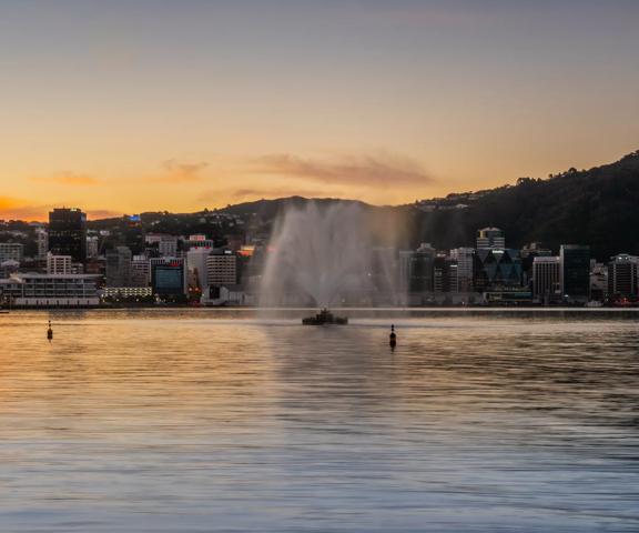 The Carter Memorial fountain spouts water at dusk with the Wellington skyline in the background.