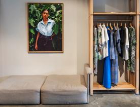 The interior of a boutique clothing store with clothes hanging neatly on hangers and a cozy seating area.