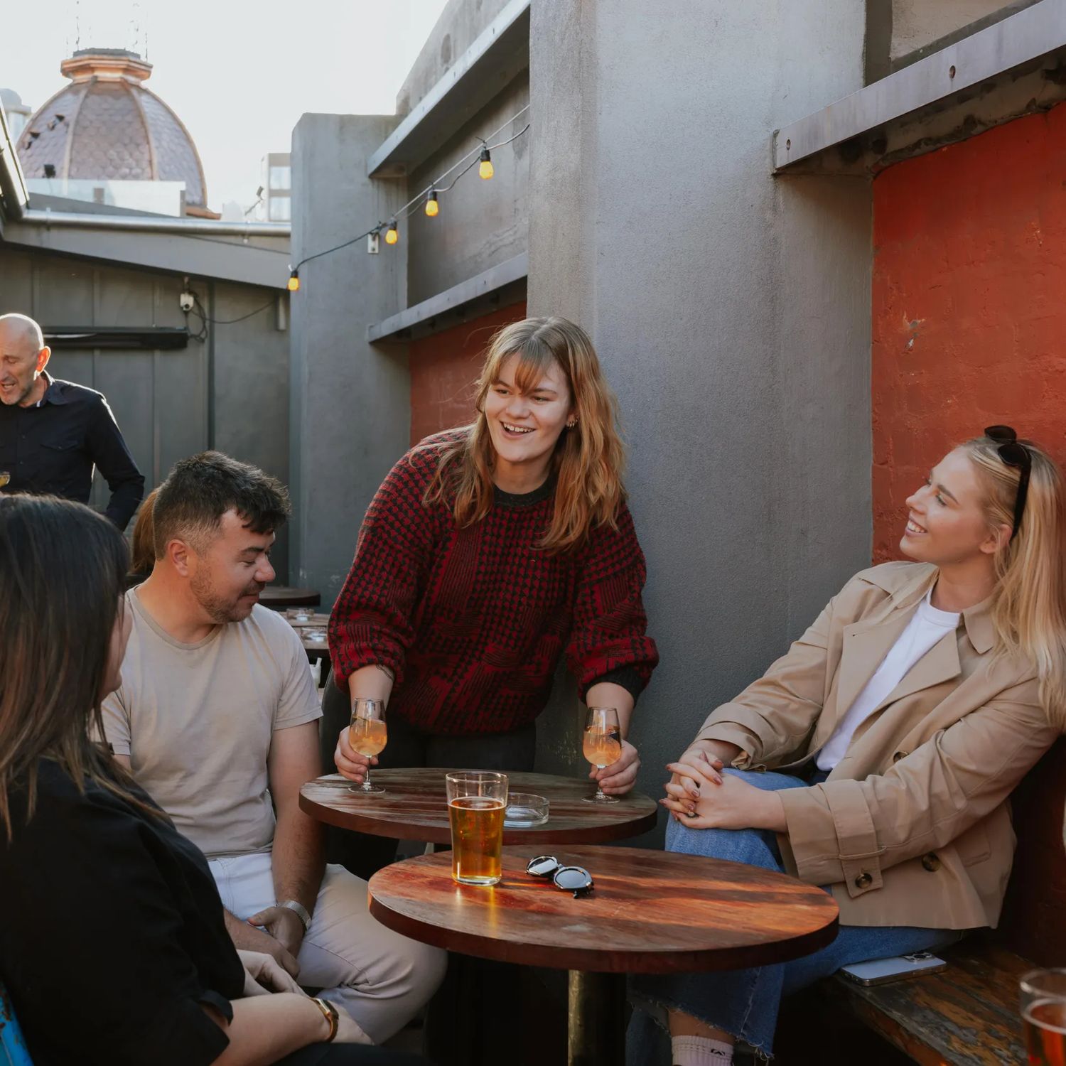 Waitstaff sets down two wine glasses in front of customers in the outside patio of Ascot.
