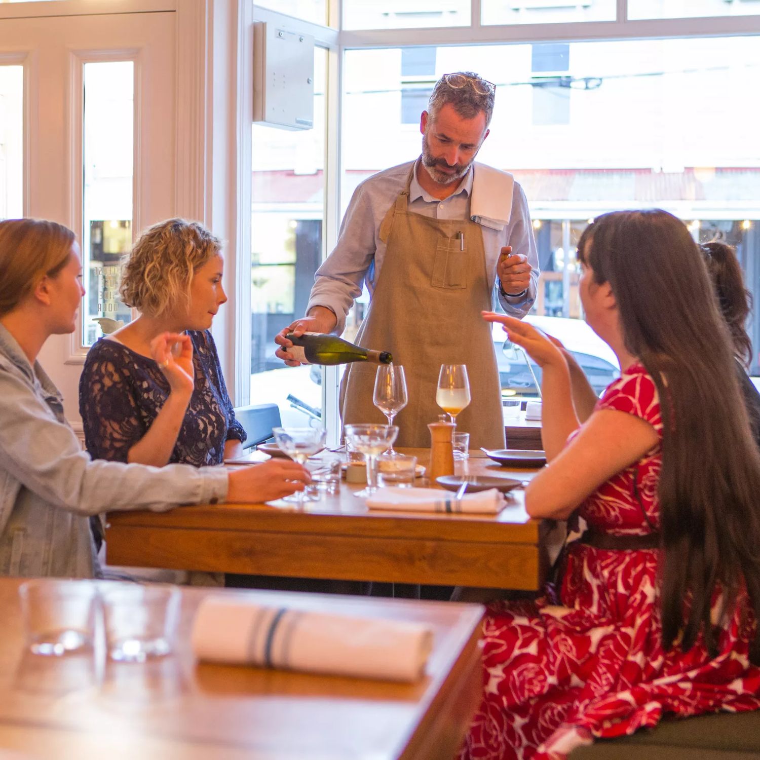 The waitstaff pouring a glass of wine for a table with 4 customers. inside Rita in Aro Valley.