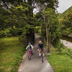 An adult and child cycle along the Hutt River Trail.